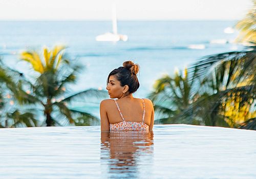 Woman in swimming pool overlooking ocean