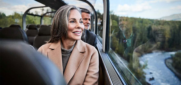 Couple look out of the window of the scenic Direct-to-the-Wilderness rail service.