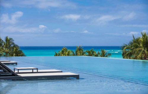 Infinity pool with aqua loungers overlooking the ocean