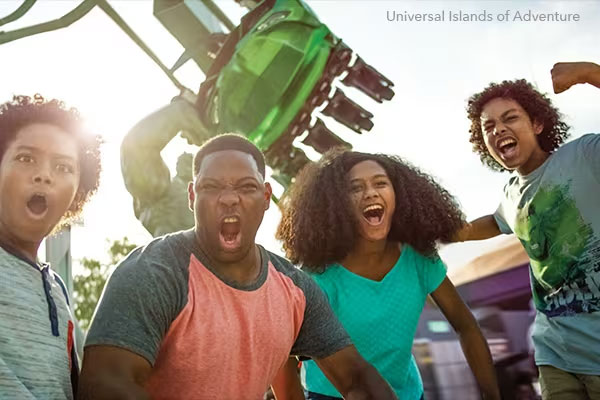 Family smiling and flexing in front of the Incredible Hulk Coaster